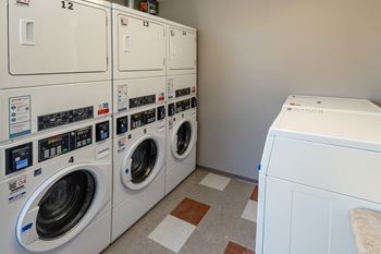 A row of washing machines are lined up in a laundry room